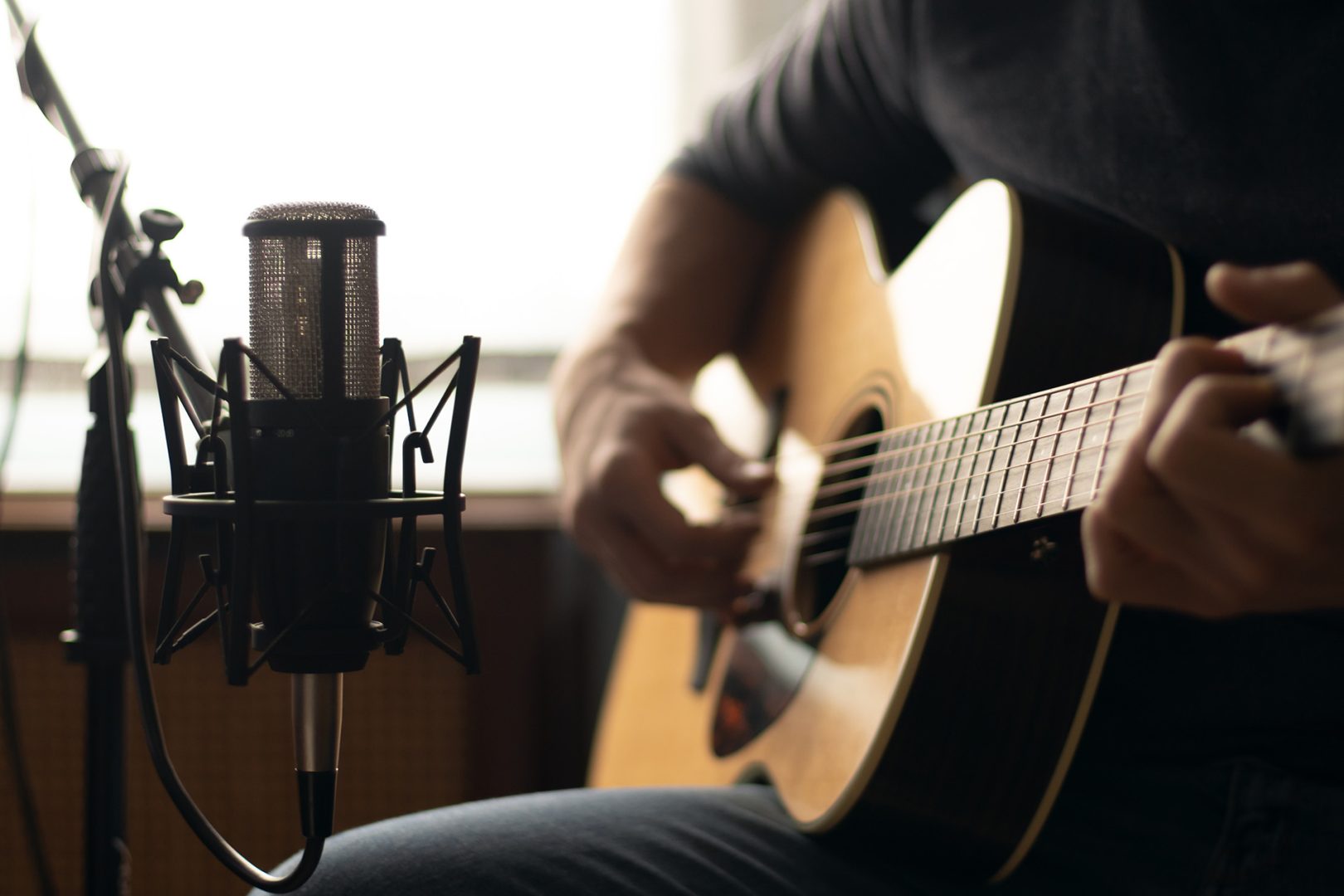 Man playing acoustic guitar and recording with a microphone in a