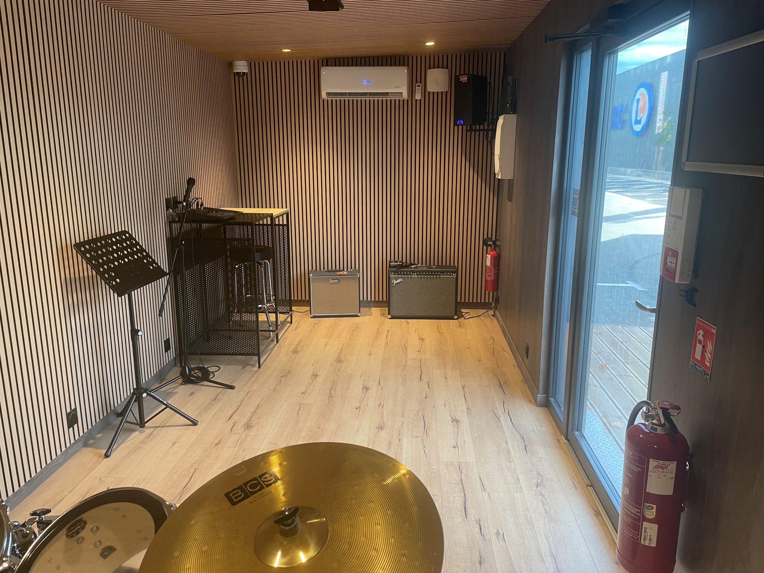 intérieur du studio de répétition avec ses amplis guitares, sa table de mixage et sa climatisation.